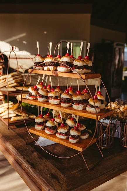 A stylish presentation of mini burgers on a wooden rack at a garden party, perfect for outdoor events.